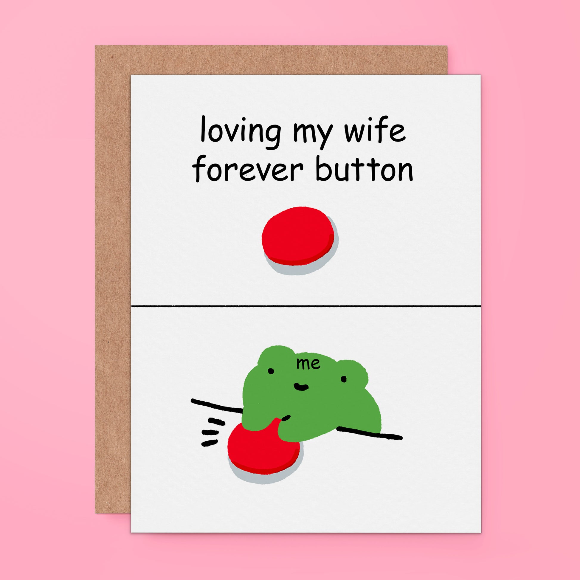 A card with a kraft envelope on a pink background. The card has a white front with the text 'loving my wife forever button' above a red button, and the bottom half shows a green cartoon frog reaching for the red button.
